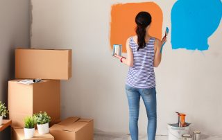 A woman compares paint colours on an accent wall
